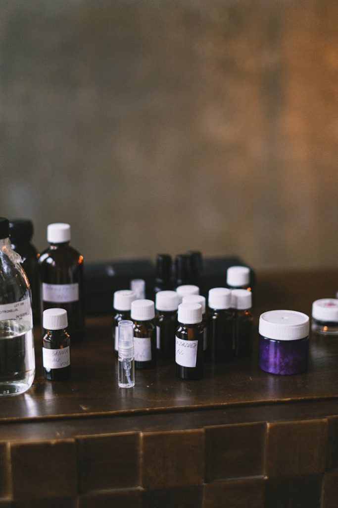 A variety of small bottles with white caps arranged on a wooden table in a dimly lit interior setting.